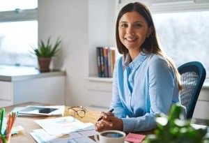 A woman smiling and working in her office. 